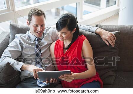 Couple looking at digital tablet together View Large Photo Image Stock Image - Couple looking at digital tablet together. Fotosearch