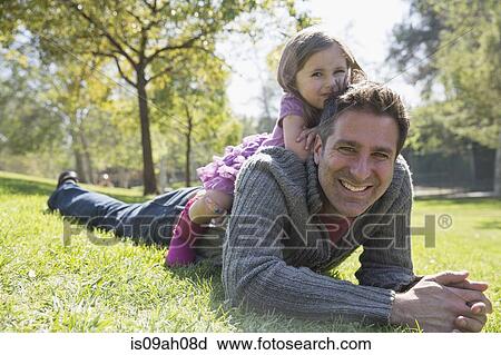 Stock Image - Father with daughter on back in park. Fotosearch