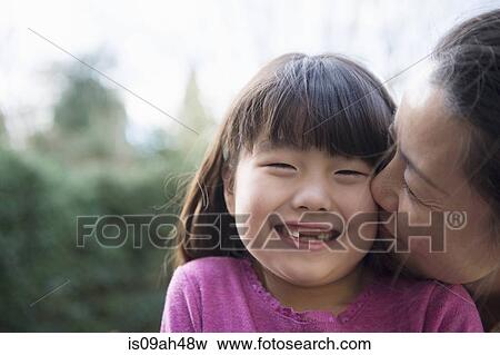 Girl being kissed on the cheek by her mother in the garden View Large Photo Image Stock Photo - Girl being kissed on the cheek by her mother in the garden. Fotosearch