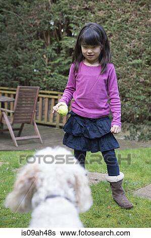 Girl playing ball with her pet dog in the garden View Large Photo Image Stock Photograph - Girl playing ball with her pet dog in the garden. Fotosearch