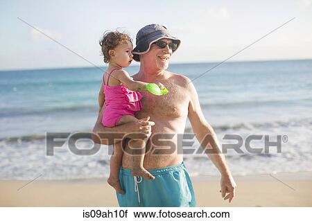 Stock Image - Grandfather and granddaughter on beach. Fotosearch