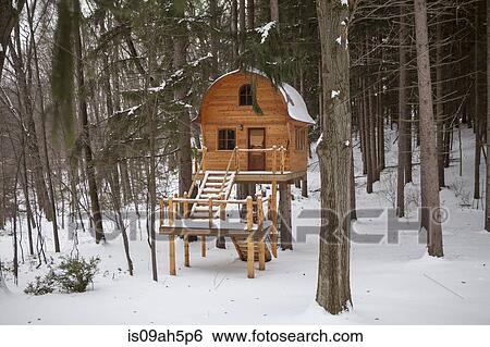 Stock Photograph - Hand built wooden chalet on stilts in snow covered forest. Fotosearch