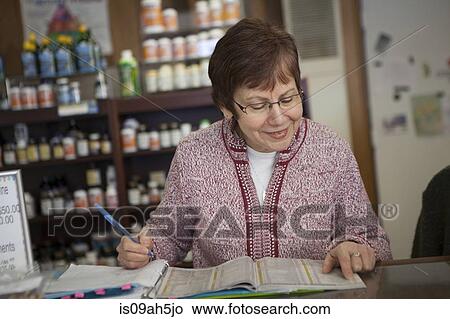 Health foods store owner doing paperwork View Large Photo Image Picture - Health foods store owner doing paperwork. Fotosearch