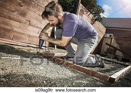 Joiner in backyard drilling wood framework View Large Photo Image Stock Photography - Joiner in backyard drilling wood framework. Fotosearch