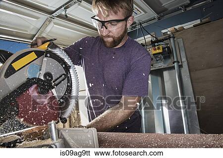 Stock Photograph - Joiner in garage using circular saw. Fotosearch