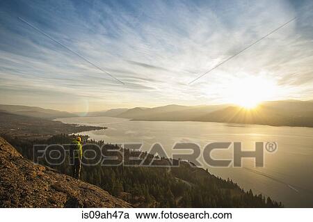 Male hiker watching sunset over Okanagan Lake, Naramata, British Columbia, Canada View Large Photo Image Stock Image - Male hiker watching sunset over Okanagan Lake, Naramata, British Columbia, Canada. Fotosearch