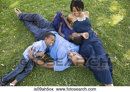 Stock Photo - Mature couple with son and daughter relaxing in park. Fotosearch
