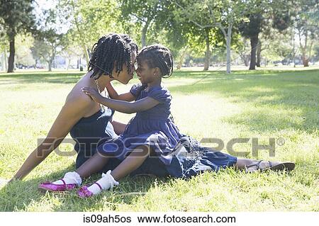Stock Photograph - Mature woman and daughter sitting in park. Fotosearch
