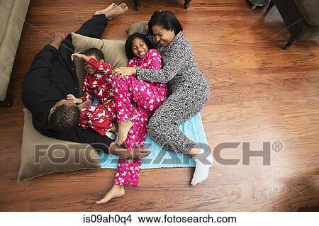 Picture - Mid adult couple and children playing on floor cushions. Fotosearch