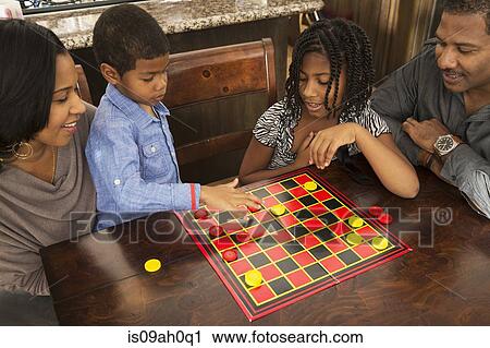 Mid adult couple and children playing draughts at dining table View Large Photo Image Stock Image - Mid adult couple and children playing draughts at dining table. Fotosearch