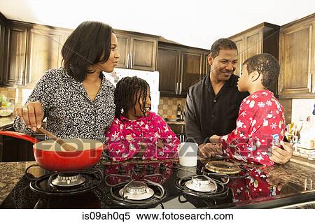 Stock Photography - Mid adult couple and children preparing breakfast. Fotosearch