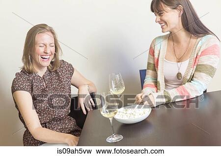 Mid adult female friends drinking white wine and laughing View Large Photo Image Stock Photo - Mid adult female friends drinking white wine and laughing. Fotosearch