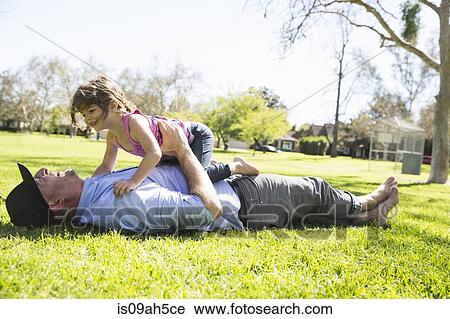 Stock Image - Mid adult man enjoying the park with young daughter. Fotosearch