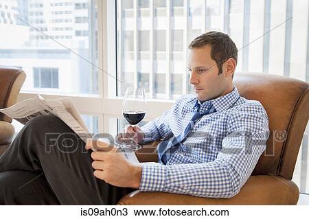 Mid adult man relaxing at home with wine and newspaper View Large Photo Image Stock Image - Mid adult man relaxing at home with wine and newspaper. Fotosearch