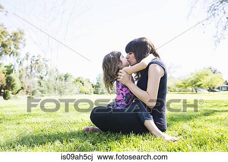 Mid adult woman and young daughter sitting in park View Large Photo Image Stock Image - Mid adult woman and young daughter sitting in park. Fotosearch