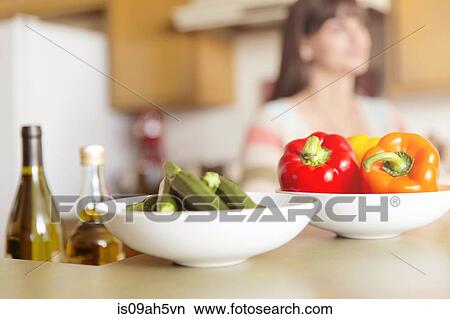 Mid adult woman in kitchen with bowls of vegetables on counter View Large Photo Image Picture - Mid adult woman in kitchen with bowls of vegetables on counter. Fotosearch