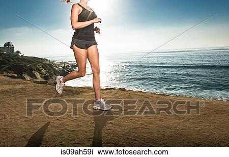 Mid adult woman jogging along cliff View Large Photo Image Stock Image - Mid adult woman jogging along cliff. Fotosearch