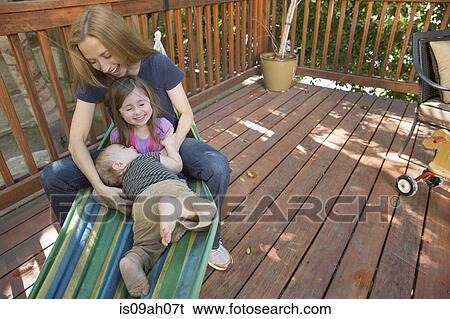 Stock Photograph - Mother and children playing on hammock. Fotosearch