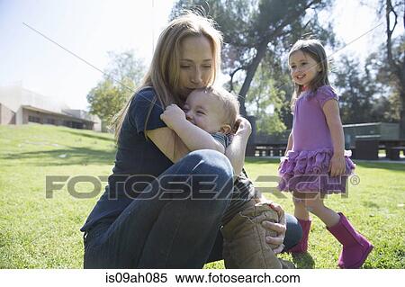 Mother hugging baby, daughter in background View Large Photo Image Stock Photography - Mother hugging baby, daughter in background. Fotosearch