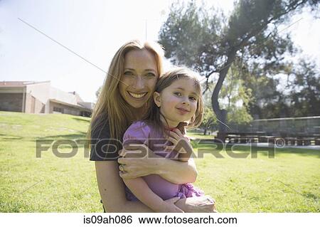 Mother hugging daughter in park View Large Photo Image Stock Photograph - Mother hugging daughter in park. Fotosearch