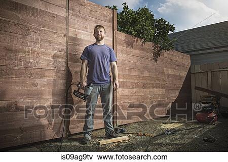 Portrait of joiner in backyard in front of new fence View Large Photo Image Stock Photo - Portrait of joiner in backyard in front of new fence. Fotosearch