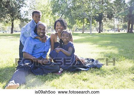 Picture - Portrait of mature couple with son and daughter sitting in park. Fotosearch