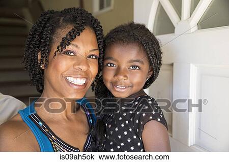 Stock Image - Portrait of mature woman and daughter at front door. Fotosearch