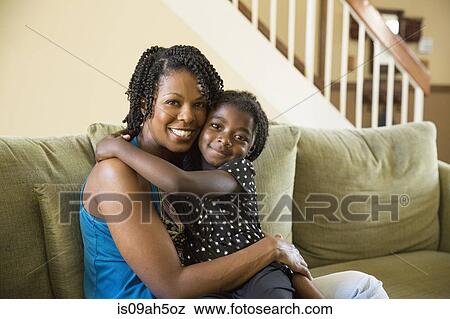 Portrait of mature woman and daughter sitting on sofa View Large Photo Image Stock Photo - Portrait of mature woman and daughter sitting on sofa. Fotosearch