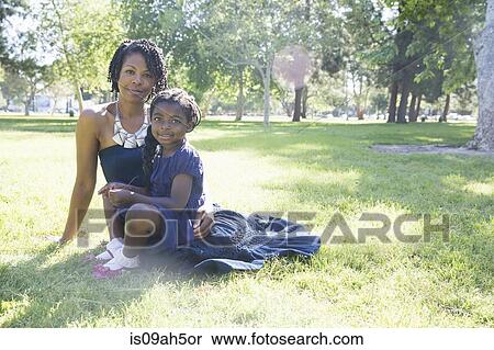 Stock Photography - Portrait of mature woman and daughter sitting in park. Fotosearch