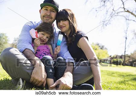 Portrait of mid adult couple and daughter sitting in park View Large Photo Image Stock Image - Portrait of mid adult couple and daughter sitting in park. Fotosearch