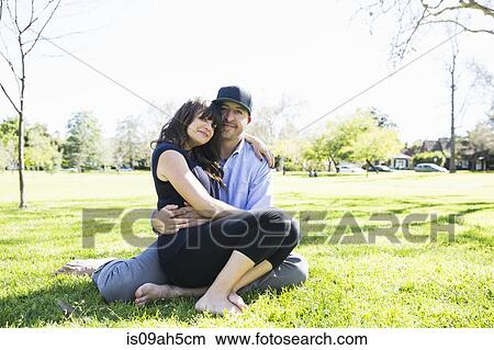 Portrait of mid adult couple sitting in park View Large Photo Image Picture - Portrait of mid adult couple sitting in park. Fotosearch
