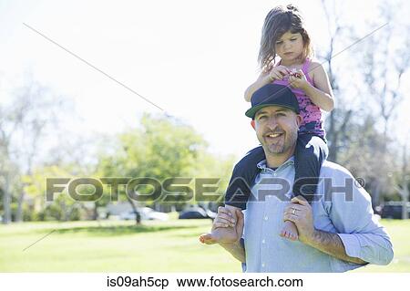 Stock Photography - Portrait of mid adult man with young daughter on his shoulders. Fotosearch