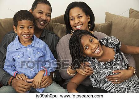 Stock Photograph - Portrait of mid adult parents with son and daughter on sofa. Fotosearch