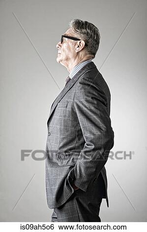 Stock Photograph - Portrait of senior man, wearing suit, side view. Fotosearch