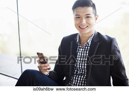 Portrait of young businessman holding smartphone View Large Photo Image Stock Photo - Portrait of young businessman holding smartphone. Fotosearch