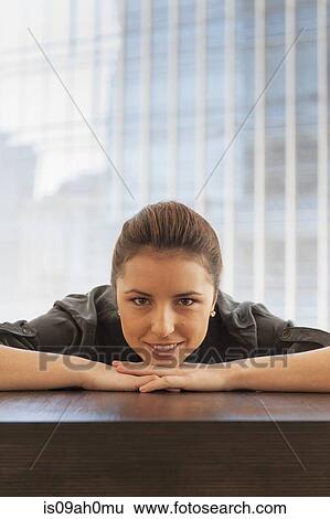 Portrait of young businesswoman leaning forward on desk View Large Photo Image Stock Photograph - Portrait of young businesswoman leaning forward on desk. Fotosearch