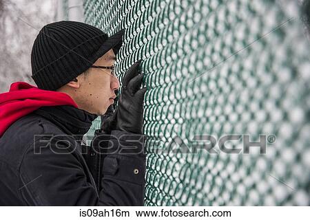 Picture - Portrait of young man looking through park fence at -30 degrees celcius. Fotosearch