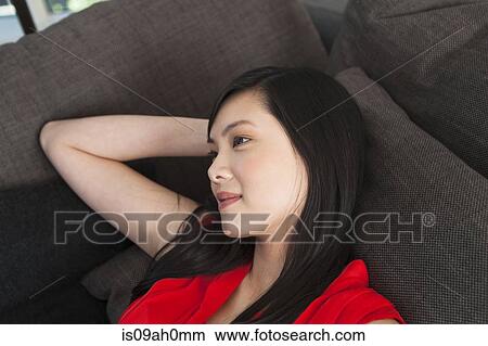 Portrait of young woman daydreaming on sofa View Large Photo Image Picture - Portrait of young woman daydreaming on sofa. Fotosearch