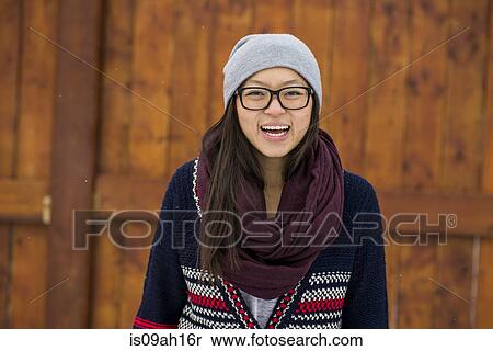 Stock Photography - Portrait of young woman in front of wooden fence. Fotosearch