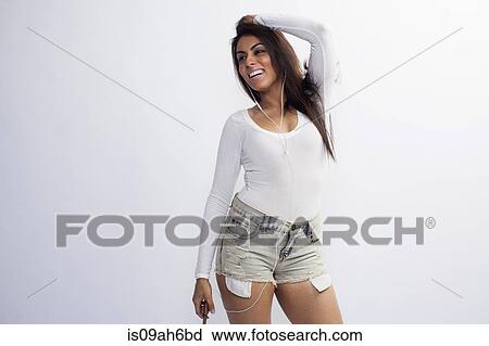 Stock Image - Portrait of young woman, listening to music. Fotosearch