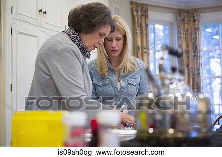 Stock Image - Senior woman and granddaughter baking together. Fotosearch