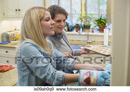 Stock Photo - Senior woman and granddaughter baking biscuits in oven. Fotosearch