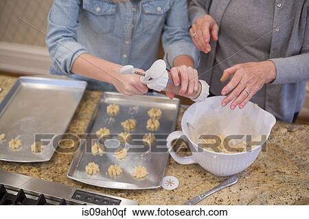 Senior woman and granddaughter piping biscuits onto baking tray View Large Photo Image Stock Image - Senior woman and granddaughter piping biscuits onto baking tray. Fotosearch