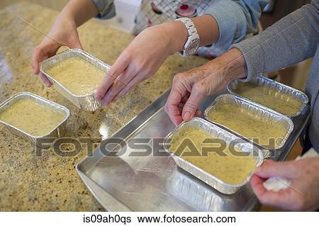 Stock Photograph - Senior woman and granddaughter preparing baking tins. Fotosearch