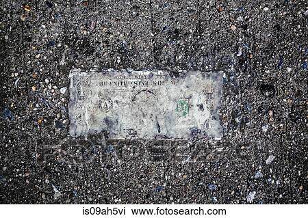 Stock Image - Still life of deteriorating one dollar bill on wet pavement. Fotosearch