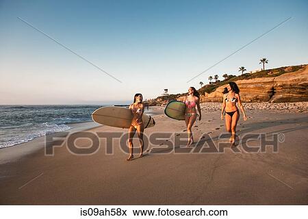 Surfers carrying surf boards, walking along beach View Large Photo Image Stock Photo - Surfers carrying surf boards, walking along beach. Fotosearch