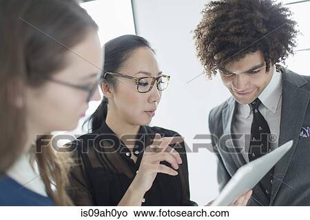 Three colleagues using digital tablet View Large Photo Image Picture - Three colleagues using digital tablet. Fotosearch