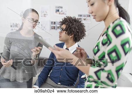 Three colleagues using digital tablet View Large Photo Image Picture - Three colleagues using digital tablet. Fotosearch