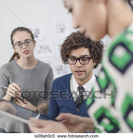 Stock Image - Three colleagues using digital tablet. Fotosearch