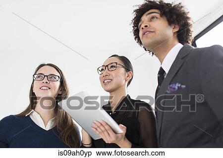 Three colleagues using digital tablet View Large Photo Image Stock Photography - Three colleagues using digital tablet. Fotosearch